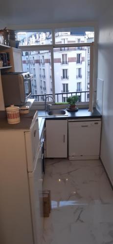una cucina con lavandino e una grande finestra di Chambre chez l’habitant près de Tour Eiffel a Parigi