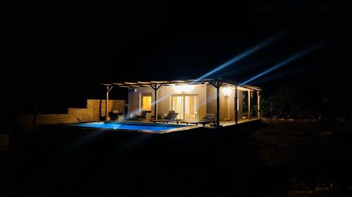 a house lit up at night with a swimming pool at Andromeda in Tsoútsouros