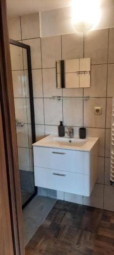 a bathroom with a white sink and a mirror at Domek przy Złotym Groniu in Istebna
