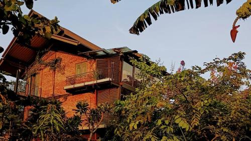 Edificio alto de ladrillo con balcón y árboles en TRANQUIL Tropical Hideaway en Kaduwela