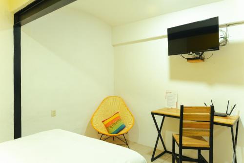 a bedroom with a bed and a desk and a tv at Casa Don José: GIRASOLES Suite in Oaxaca City