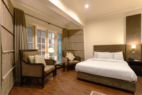 um quarto de hotel com uma cama e uma cadeira em Shelton Rezidor House Peshawar em Peshawar