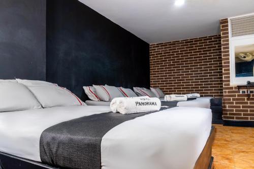 1 dormitorio con 1 cama grande y pared de ladrillo en Hotel Panorama Center, en Medellín