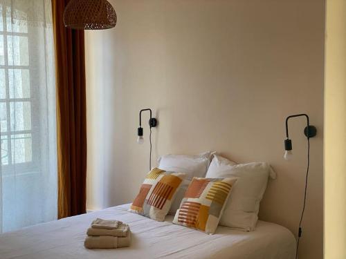 a bed with two pillows and a lamp on it at Le Prieuré du Vigeant in Le Vigeant