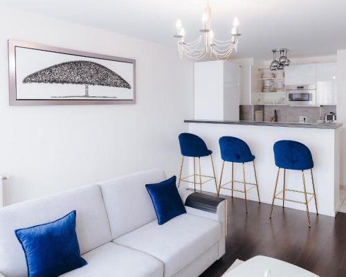 - un salon avec un canapé blanc et des fauteuils bleus dans l'établissement Appartement luxueux, neuf & équipé à VERSAILLES, SAINT-CYR-L'ÉCOLE, à Saint-Cyr-lʼÉcole