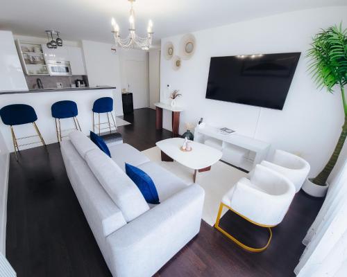 ein Wohnzimmer mit einem weißen Sofa und blauen Stühlen in der Unterkunft Appartement luxueux, neuf et équipé à VERSAILLES, ST CYR L'ÉCOLE in Saint-Cyr-lʼÉcole