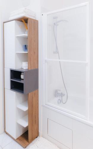 La salle de bains est pourvue d'une douche et d'une armoire blanche. dans l'établissement Appartement luxueux, neuf & équipé à VERSAILLES, SAINT-CYR-L'ÉCOLE, à Saint-Cyr-lʼÉcole