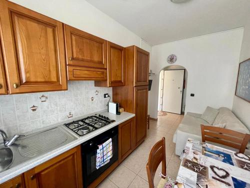 a kitchen with wooden cabinets and a stove top oven at Appartamento Villa Asio in Lignano Sabbiadoro