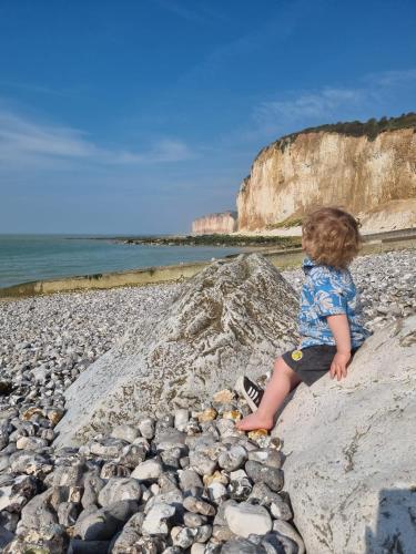 a young child sitting on a rocky beach at Le Relais des Trois Cépages in Sassetot-le-Mauconduit