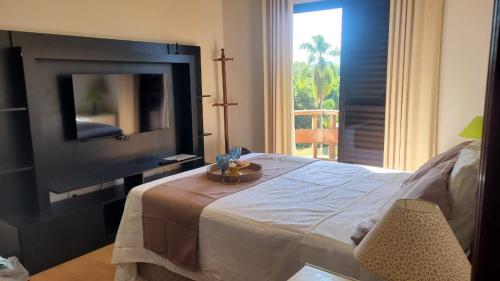 1 dormitorio con 1 cama, TV y silla en Apartamento flat em Serra Negra - 12A, en Serra Negra