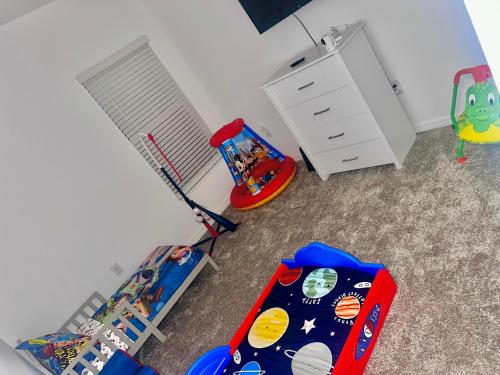 a childs room with a table and a crib and an umbrella at Brand New Home by LegoLandPeppa Pig Park! in Lake Wales