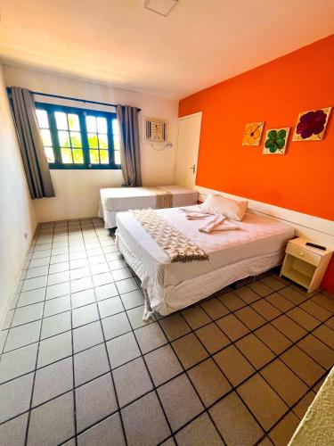 a bedroom with two beds and an orange wall at Pousada Pedras do Porto in Porto De Galinhas