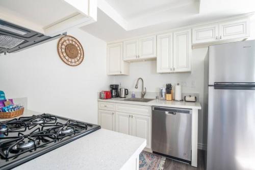 a kitchen with white cabinets and a stainless steel refrigerator at Enjoy Alhambra Night Life at 2BR Apt in Alhambra