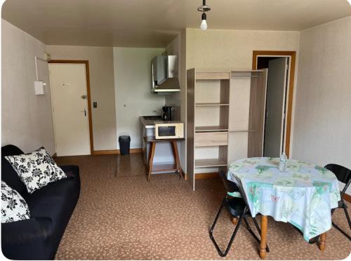 a living room with a table and a kitchen at Studio meublé tout confort in Bourbonne-les-Bains