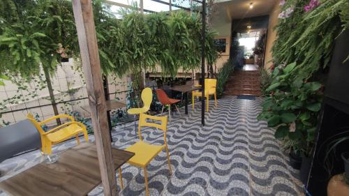 a room with yellow chairs and tables and plants at Pousada Casa dos Gattos - Próx ao Aeroporto Guarulhos in Guarulhos