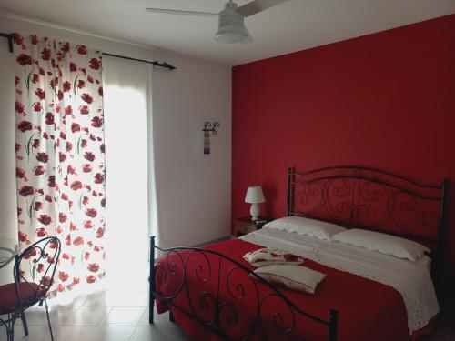 um quarto vermelho com uma cama e uma janela em Sunrise em Lascari