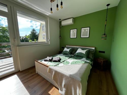 a bedroom with a bed with green walls and a window at Csicsergő Zamárdi in Zamárdi