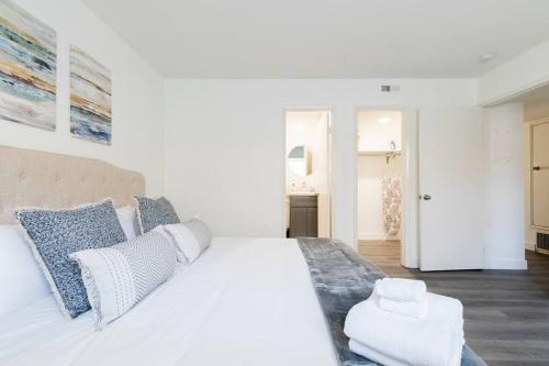 a white bedroom with a large bed with blue pillows at City Retreat Minutes to DT in Alhambra
