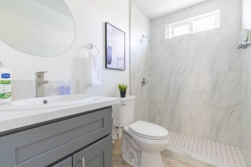 a white bathroom with a toilet and a sink at City Retreat Minutes to DT in Alhambra
