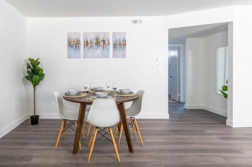 a dining room with a wooden table and white chairs at City Retreat Minutes to DT in Alhambra
