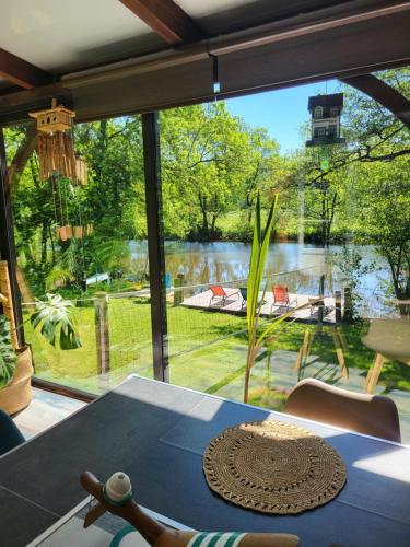 een kamer met een tafel en uitzicht op een meer bij Maison de vacances: chez Nirina in Mortagne-sur-Sèvre