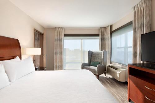 une chambre d'hôtel avec un lit, une chaise et une fenêtre dans l'établissement Hilton Garden Inn Troy, à Troy