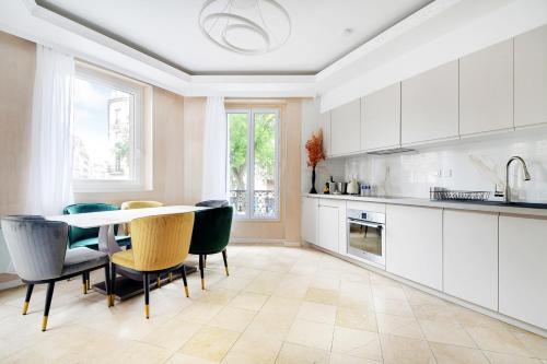 une cuisine avec des armoires blanches et une table et des chaises dans l'établissement Vivez au coeur du centre de Paris! Métro à 1min - Proche Republique, à Paris