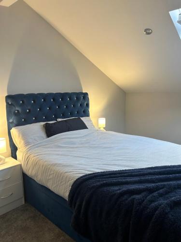 Bett mit blauem Kopfteil in einem Zimmer in der Unterkunft The Luxe By Elegant Aparts in Bradford