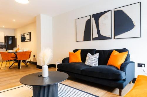 a living room with a black couch and orange pillows at The Berriman Collection Stylish 2 Bedroom Apartment in Cardiff