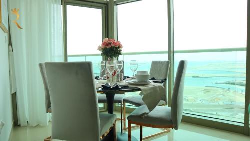 a dining room with a table and chairs in front of a window at Modern 1BR Stay - Sleek Chic Cozy Haven in Abu Dhabi