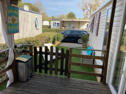 un porche avec une clôture, une télévision et une voiture dans l'établissement La Carabasse 4 étoiles Mobilhome 6 personnes, 3 chambres tout confort, à Vias