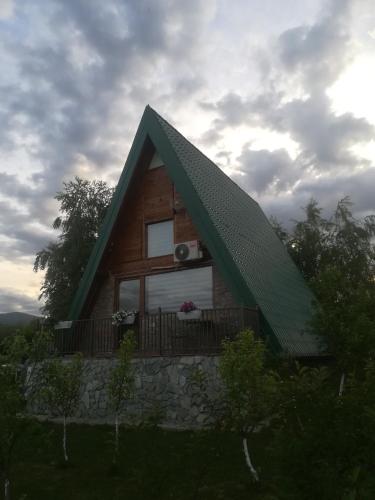 a log cabin with a green roof and a balcony at Banjska brvnara in Vrnjačka Banja