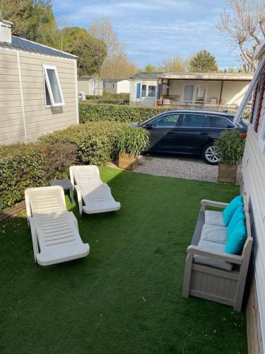 une cour arrière avec deux chaises de jardin et deux lits dans l'établissement La Carabasse 4 étoiles Mobilhome 6 personnes, 3 chambres tout confort, à Vias