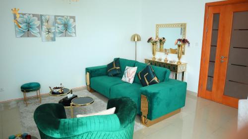 a living room with a green couch and two chairs at Modern 1BR Stay - Sleek Chic Cozy Haven in Abu Dhabi