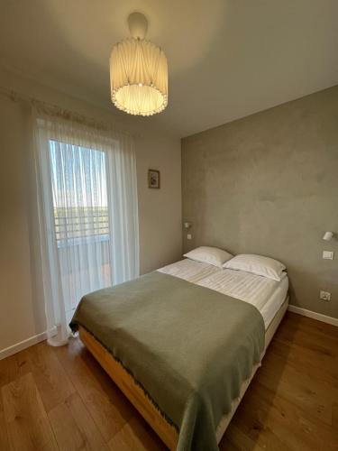 a bedroom with a large bed and a chandelier at Apartament Nowe Ogrody in Leszno