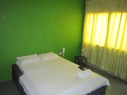 Dormitorio verde con cama blanca y pared verde en Hospedaje Talareño Hokua Suite, en Talara