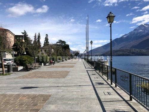 a sidewalk next to a body of water with mountains at Casa Regina in Dongo