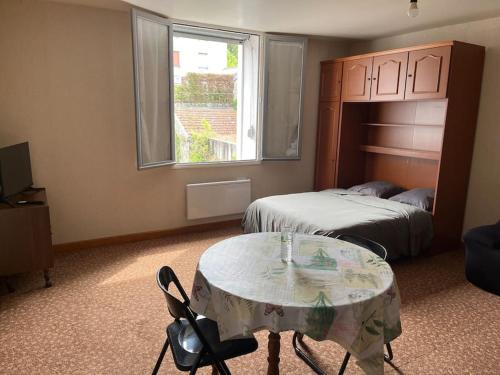 Cette chambre comprend une table, un lit et une fenêtre. dans l'établissement Grand studio proche commerces, à Bourbonne-les-Bains