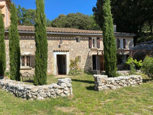 une ancienne maison en pierre avec des arbres devant elle dans l'établissement La Bastide Basse Nature Piscine à 3 quarts d'heure de la mer, à Signes