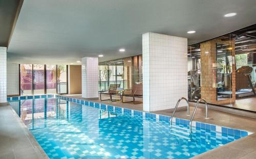 a large swimming pool with blue tiles in a building at Apartamento em Hotel 4 estrelas - Moema in Sao Paulo