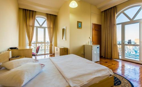 a bedroom with a large bed and a large window at Red Roof Seaview Hotel in Baku