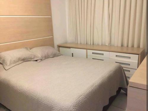 1 dormitorio con cama blanca y escritorio en Apartamento em Balneário Camboriú, en Balneário Camboriú