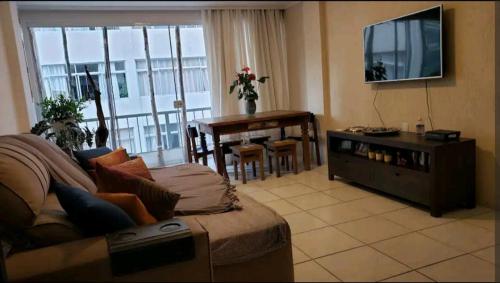 Sala de estar con sofá, TV y mesa en Apartamento em Balneário Camboriú, en Balneário Camboriú
