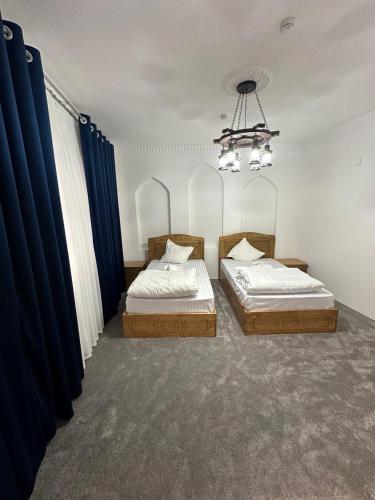 two beds in a room with blue curtains at MUNIS Plaza in Bukhara