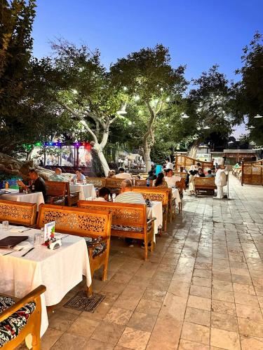 a restaurant with tables and people sitting at tables at MUNIS Hotel lyabi houz in Bukhara