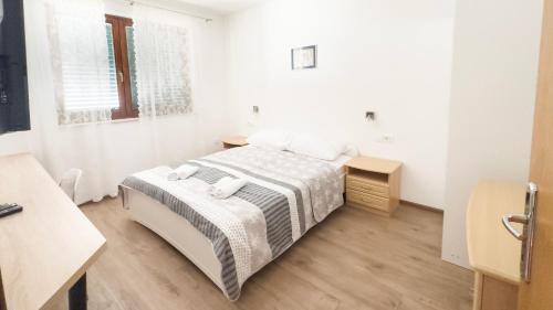 a white bedroom with a bed and a desk at Apartments Antonio in Tisno