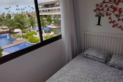 a bedroom with a window with a view of a pool at Malawi Beach Resort - Flat SKY in Porto De Galinhas
