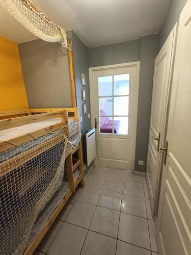 une chambre avec un berceau et une porte avec une fenêtre dans l'établissement Charmant studio en bord de mer, à Camiers