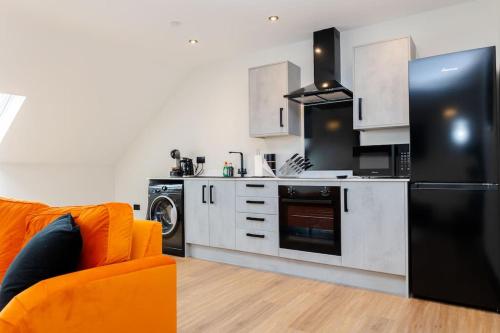 a kitchen with an orange couch and a black refrigerator at The Berriman Collection Stylish Sleeps 6 - 2 Bedroom in Cardiff