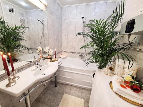 a bathroom with a sink and a tub with plants at Albina apartman in Eger
